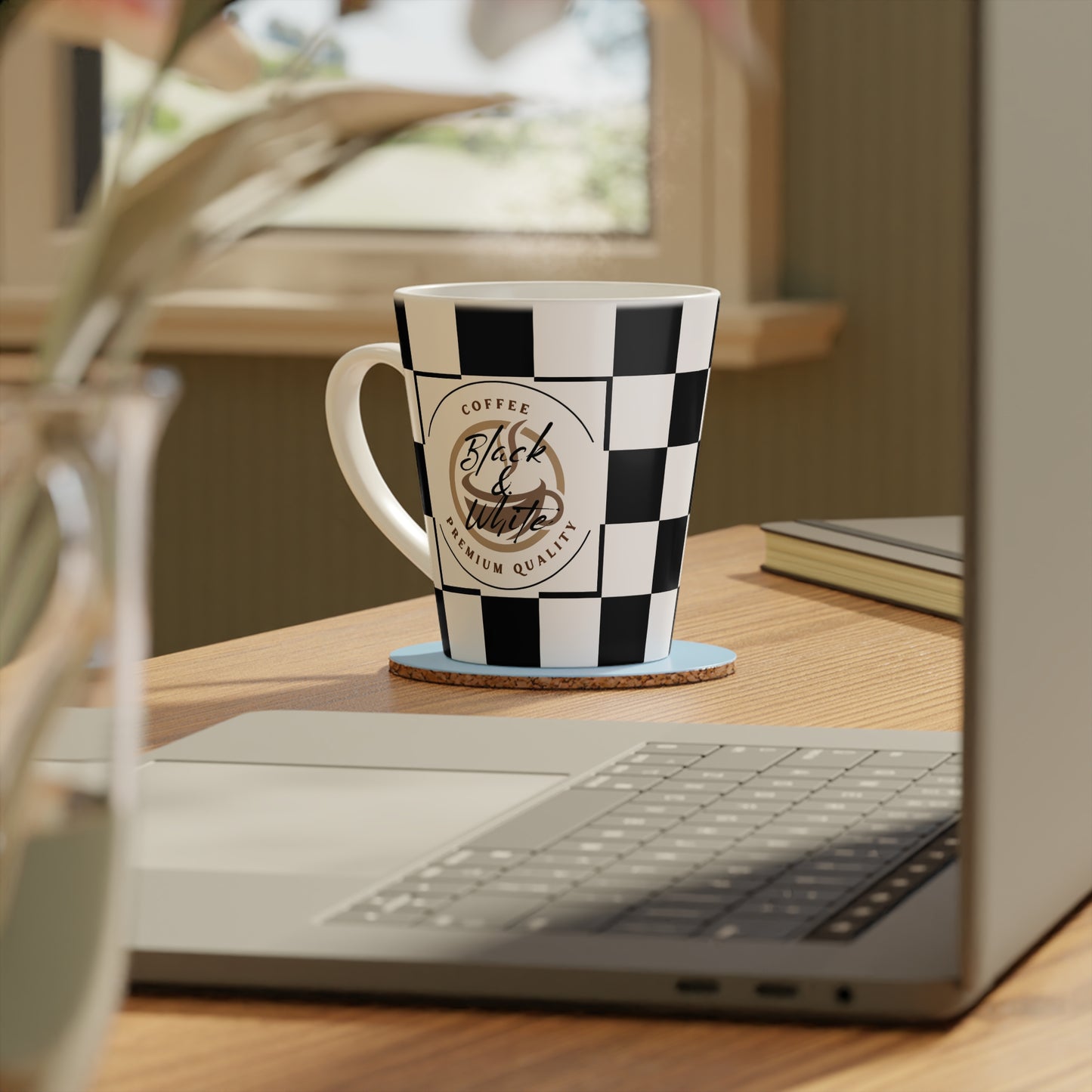 Chic Checkered Latte Mug with black and white checkered pattern sitting on a wooden desk near a laptop.