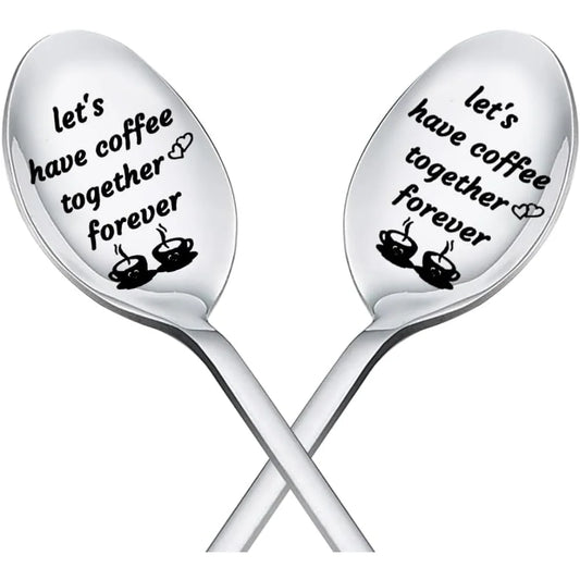 Two silver spoons with engraved text 'Let's have coffee together forever' on a white background